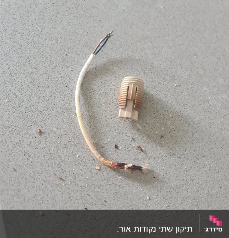 חוט חשמל חשוף ומחבר פלסטיק על משטח אפור